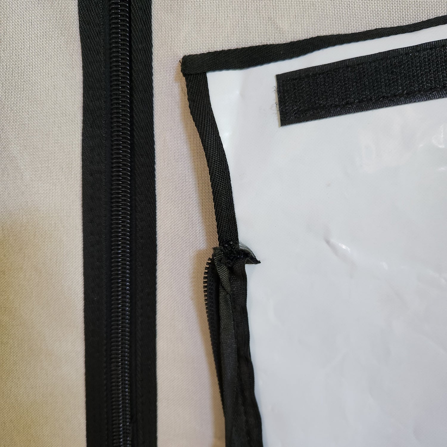 Close-up of a zipper and black trim on a white grow tent